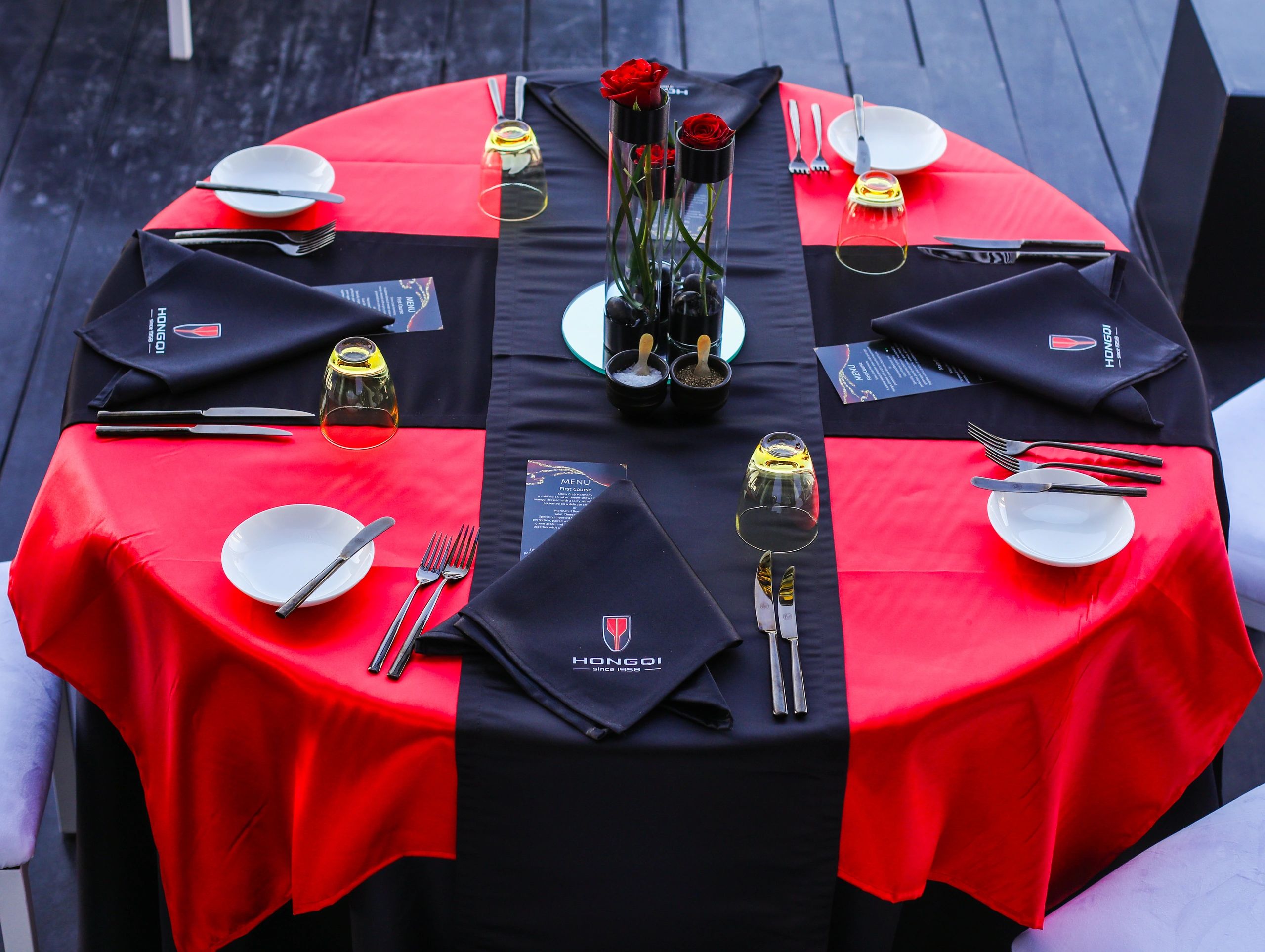 Red and black Hongqi table setting with branded napkins, menus and roses