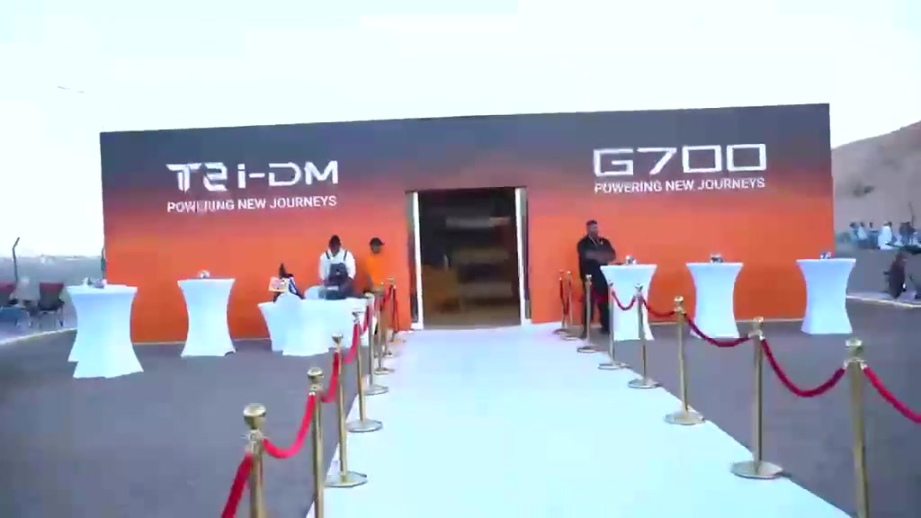 A branded Jetour entrance with an arrival carpet and cocktail tables.