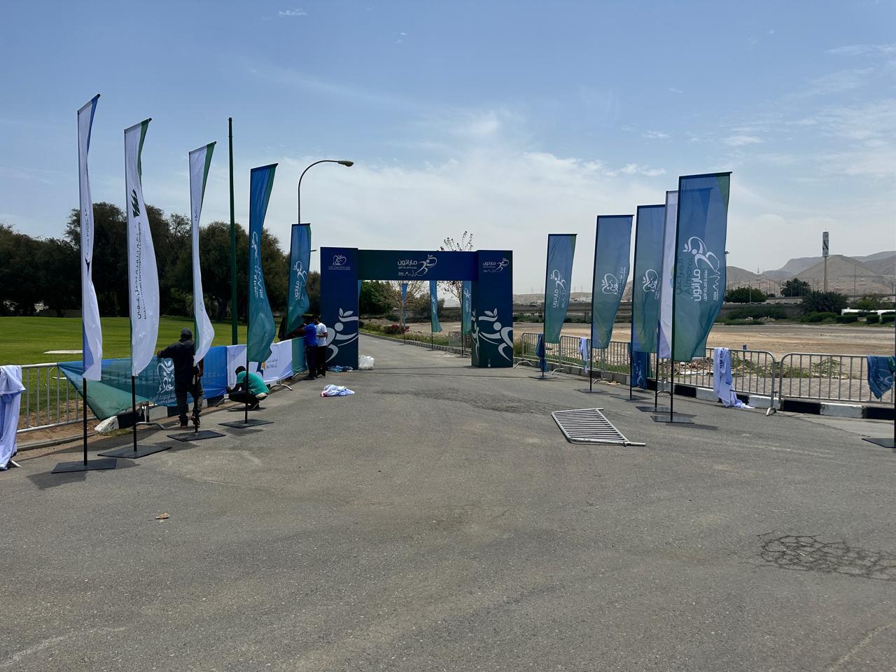 Tall branded flags leading to an event entrance arch.