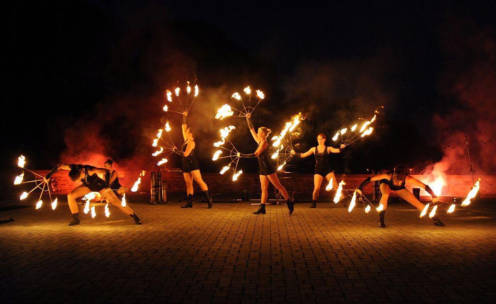 A group of fire performers presenting a choreographed outdoor show.