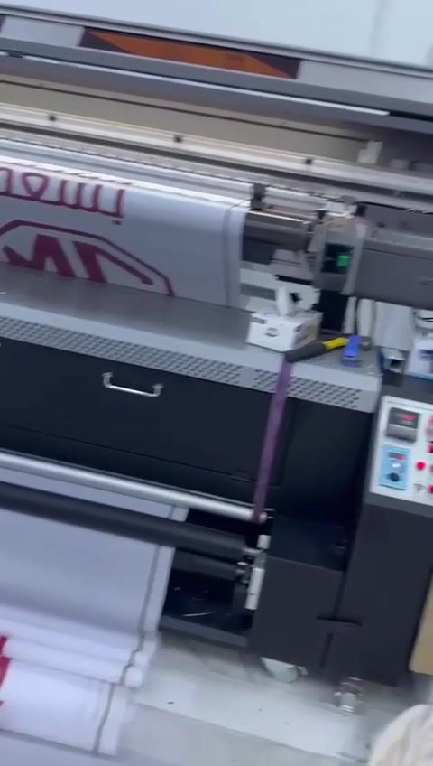 Large-format printing in progress, producing MG-branded material.